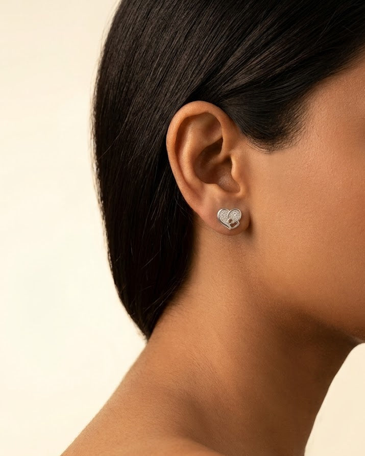 Close-up of a person wearing a heart-shaped earring on a neutral background