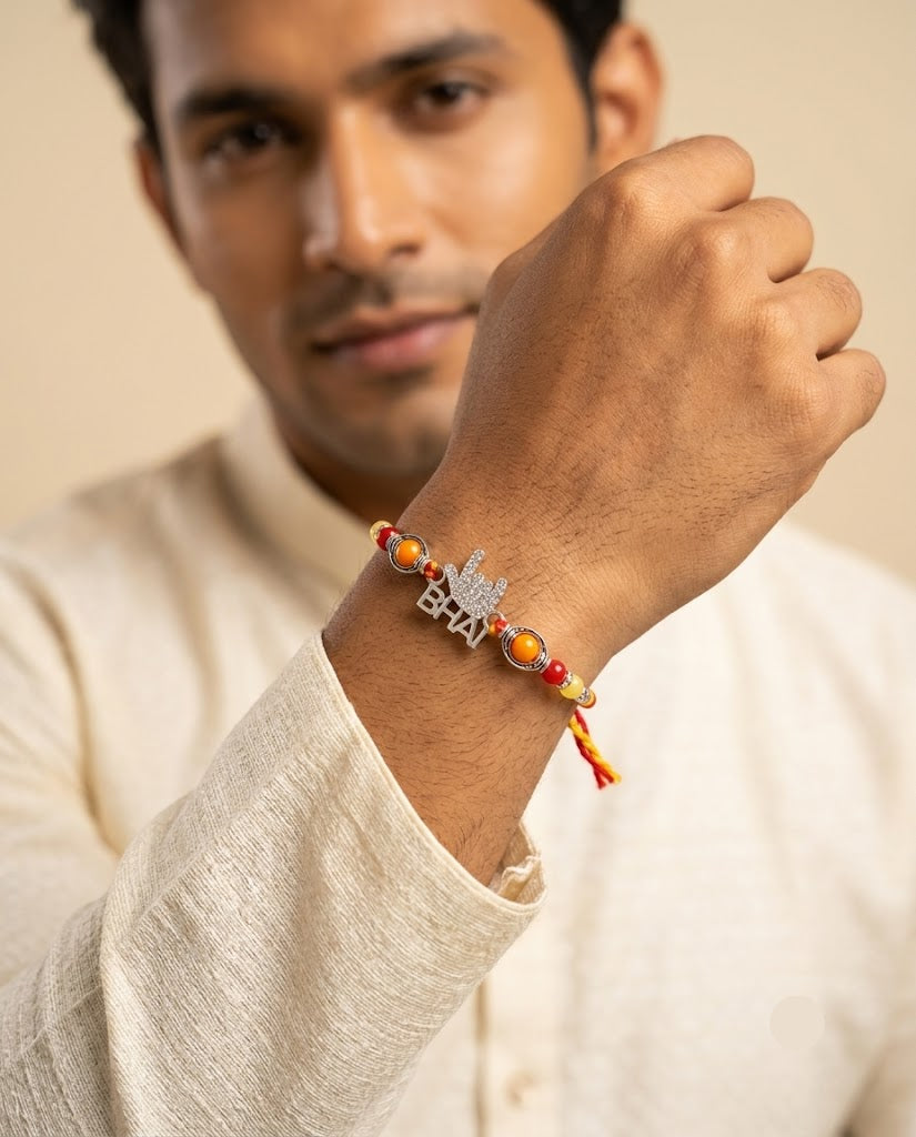 A man wearing a silver Rakhi bracelet with orange and red beads on a matching string, shown in a lifestyle close-up shot.