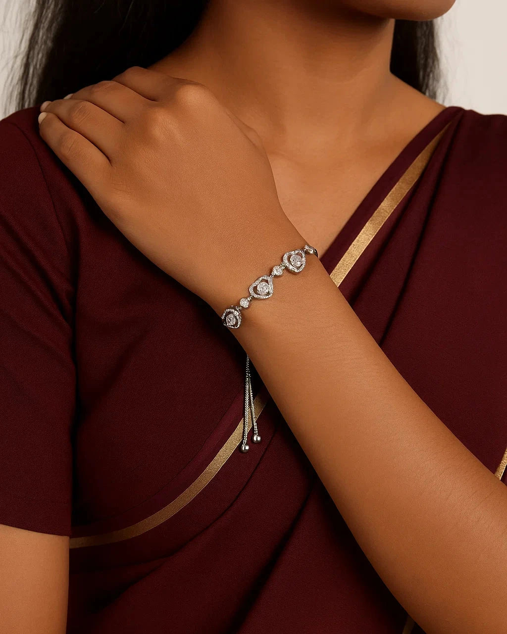 Person wearing a maroon saree with a silver bracelet