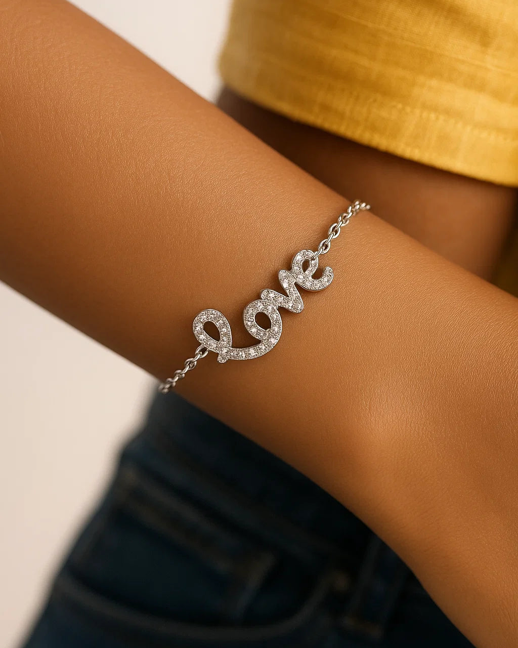 Silver 'love' bracelet on a wrist with a blurred background