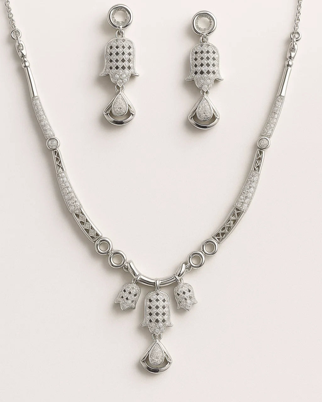 Silver necklace and earrings set on a white background