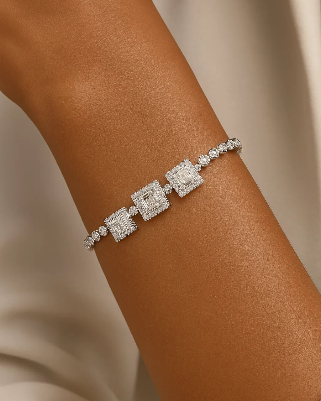 Silver bracelet with square-shaped charms on a wrist against a neutral background