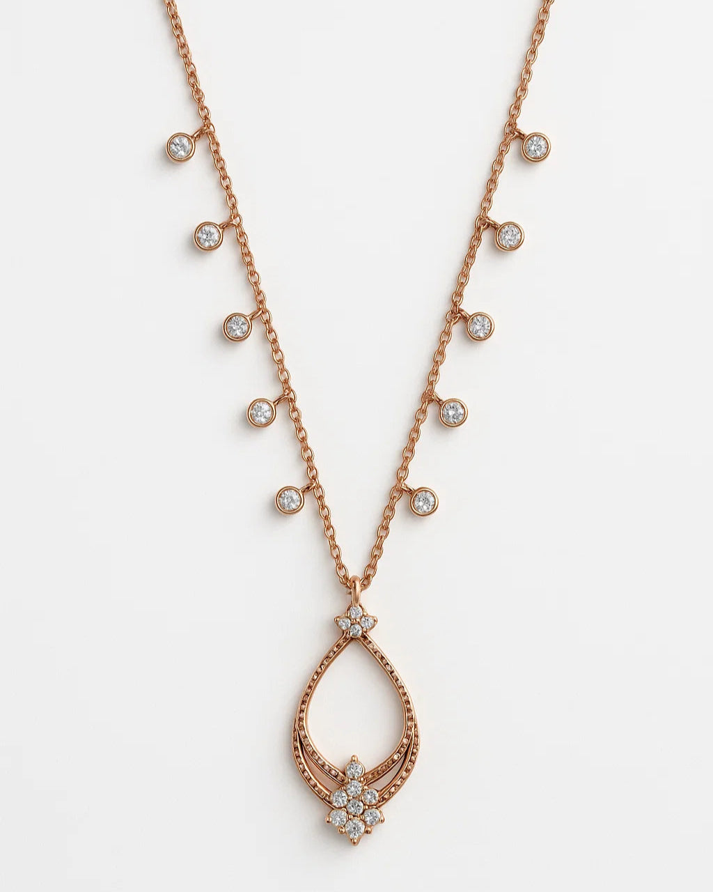 Rose gold necklace with teardrop pendant and small diamonds on a white background