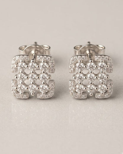 Pair of silver earrings with intricate designs on a light gray background