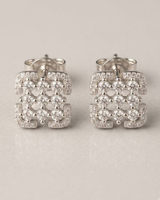 Pair of silver earrings with intricate designs on a light gray background