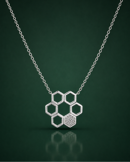 A silver honeycomb pendant necklace with one textured hexagon and five open hexagons, suspended from a delicate silver chain against a dark green gradient background.