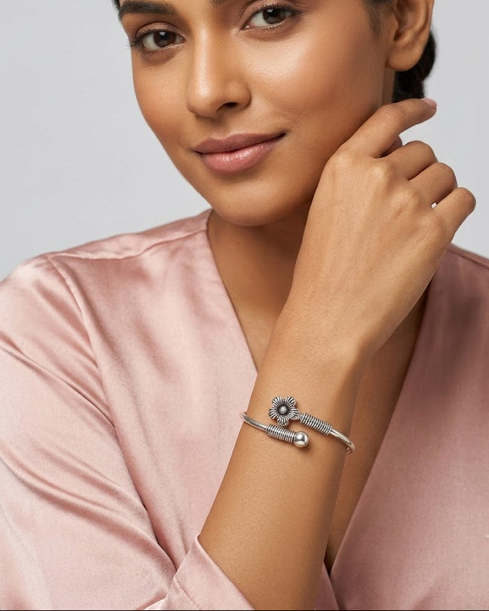 Woman wearing a silver bracelet with a subtle design on a plain background