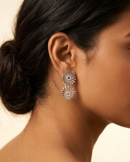 Close-up of a woman wearing silver earrings with a neutral background