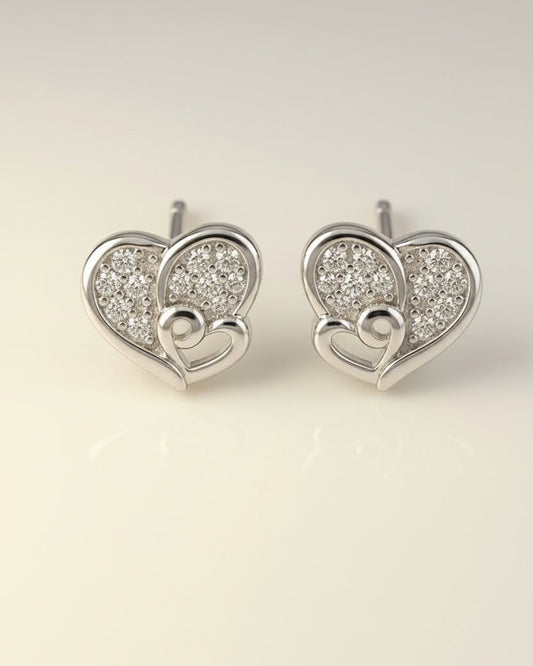 Heart-shaped silver earrings with embedded stones on a light beige background