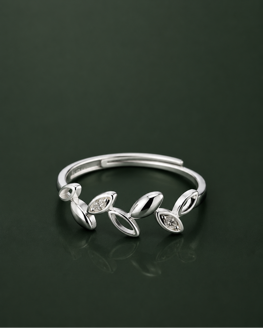 A silver adjustable ring featuring a series of stylized leaf and oval motifs, some of which are set with small clear marquise-cut stones, displayed on a dark reflective surface.