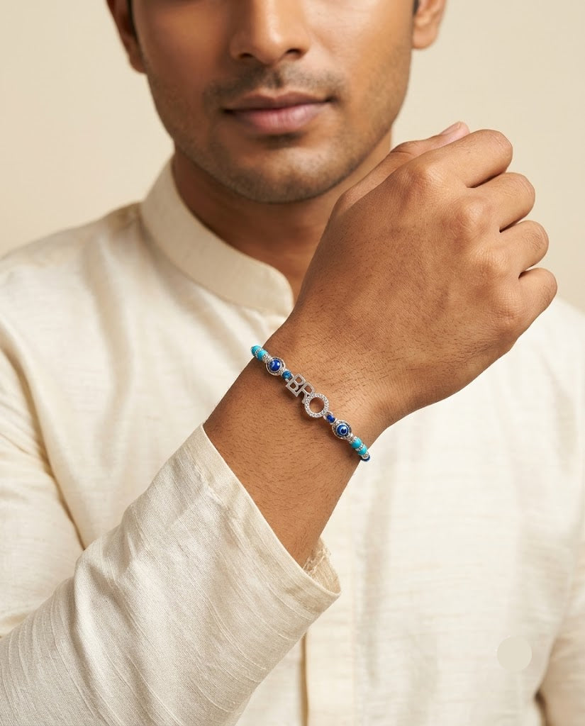 A man wearing a light beige kurta and adjusting his wrist with a beaded bracelet featuring turquoise blue beads, a silver-toned metal chain, and a white circular bead.