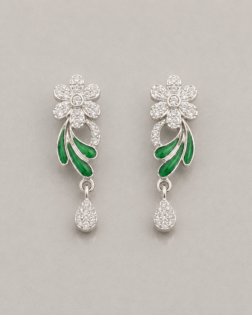 Floral earrings with green leaves and clear stones on a gray background
