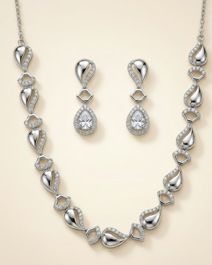 Silver necklace and earrings set on a beige background
