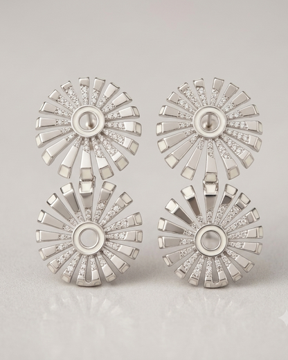 Set of silver earrings with starburst design on a light gray background