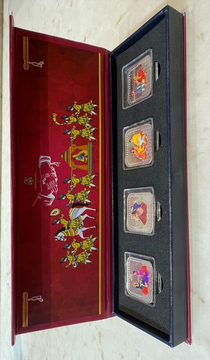 Set of four silver coins in a decorative box with illustrations on a white background