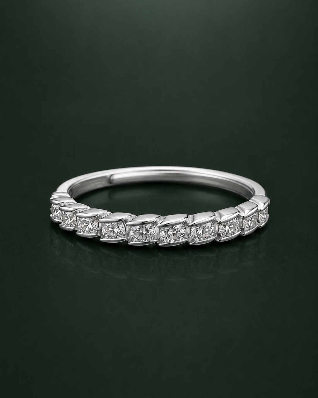 A silver cz-diamond eternity ring with a continuous line of small round-cut diamonds set in a polished silver band, displayed on a dark green reflective surface.