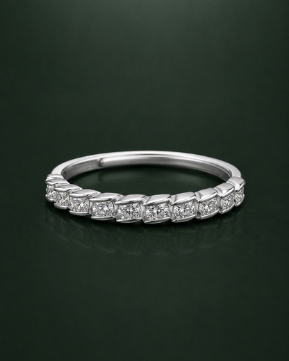 A silver cz-diamond eternity ring with a continuous line of small round-cut diamonds set in a polished silver band, displayed on a dark green reflective surface.
