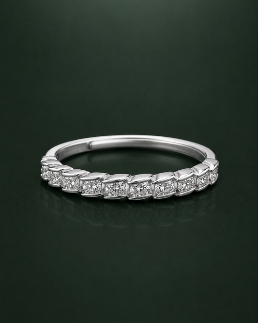 A silver cz-diamond eternity ring with a continuous line of small round-cut diamonds set in a polished silver band, displayed on a dark green reflective surface.