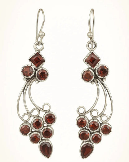 Pair of silver earrings with red gemstones on a white background