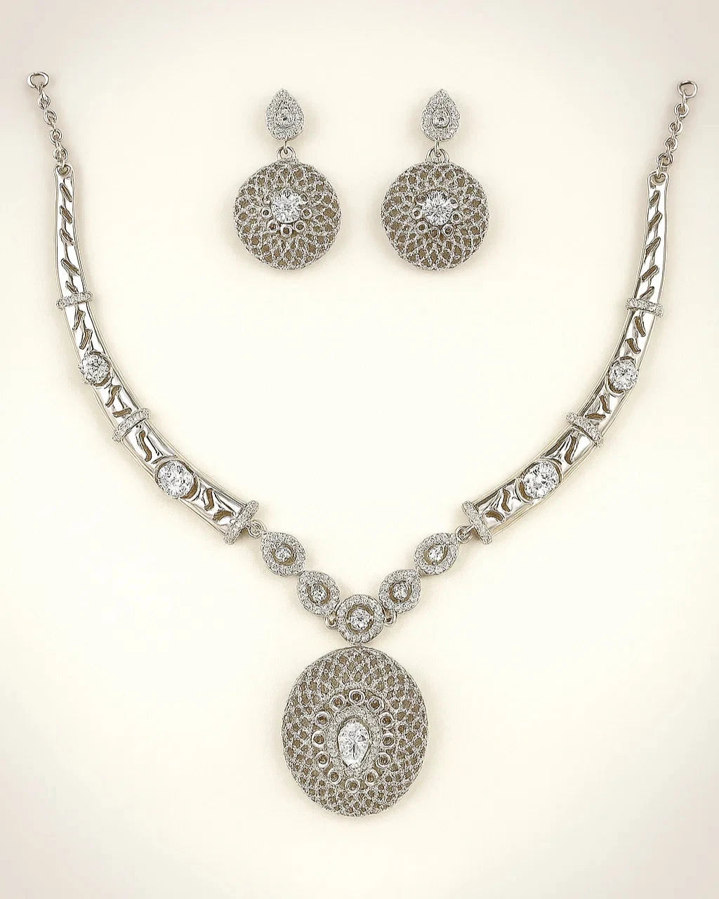 Silver necklace and earrings set on a light background
