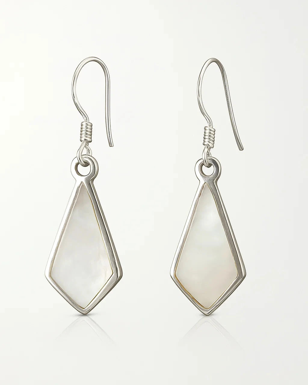 Pair of silver earrings with teardrop-shaped white stones on a light gray background