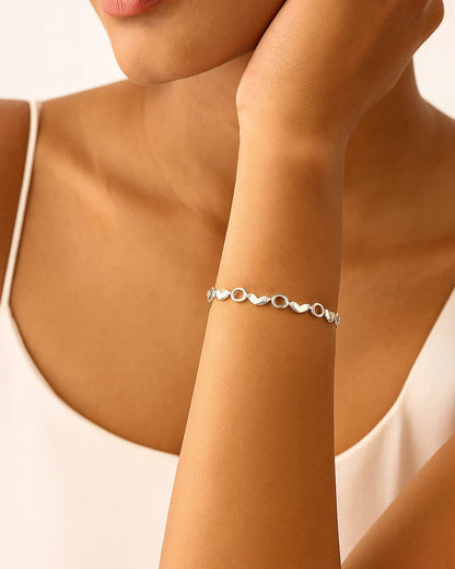 Silver bracelet on a person's wrist with a neutral background