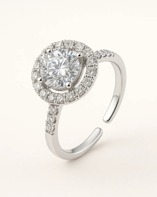 Silver ring with a large central gemstone and smaller stones around on a white background