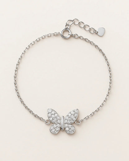 Silver butterfly bracelet with clear stones on a light beige background