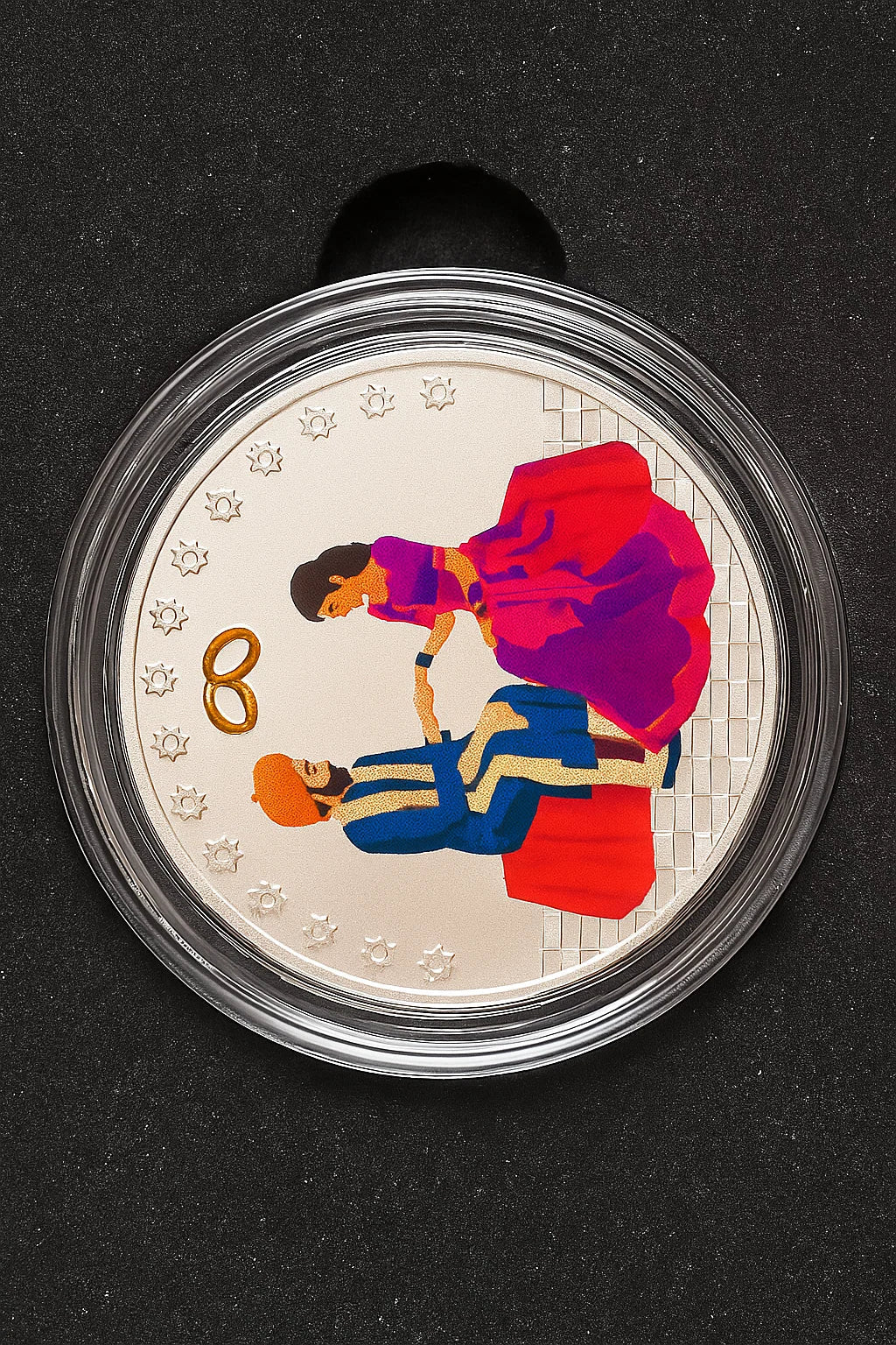 Coin with illustration of a couple and wedding rings on a black background