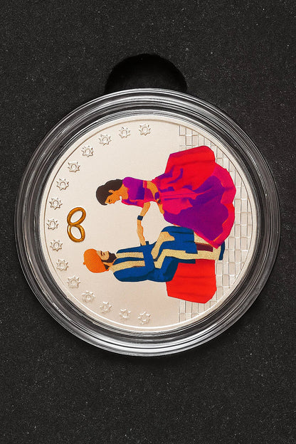 Coin with illustration of a couple and wedding rings on a black background