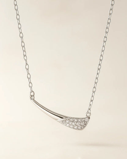 Silver necklace with a curved pendant on a light background