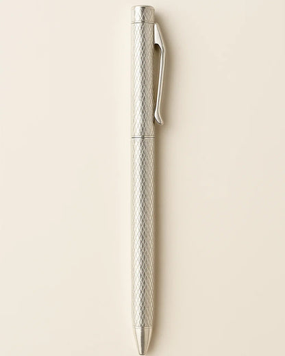 Silver pen with textured design on a beige background