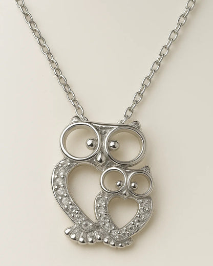 Silver owl-shaped pendant on a chain against a light background