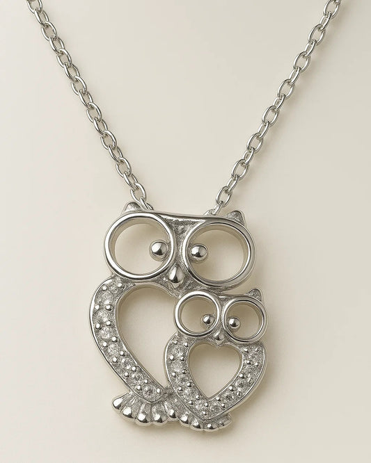 Silver owl-shaped pendant on a chain against a light background