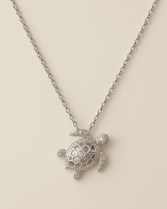 Silver turtle pendant necklace on a beige background