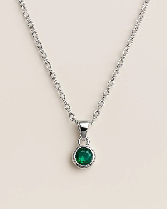 Silver necklace with a green gemstone pendant on a beige background