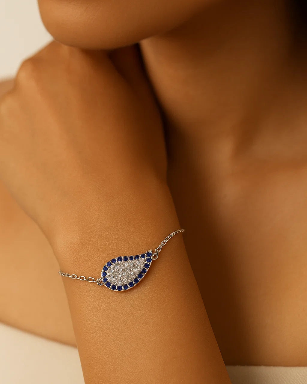 Close-up of a person wearing a silver bracelet with blue accents on a neutral background