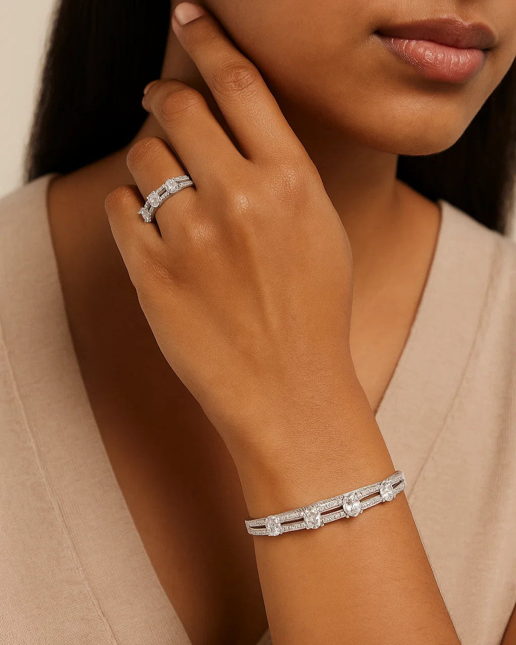 Close-up of a woman wearing a silver bracelet and ring on a neutral background