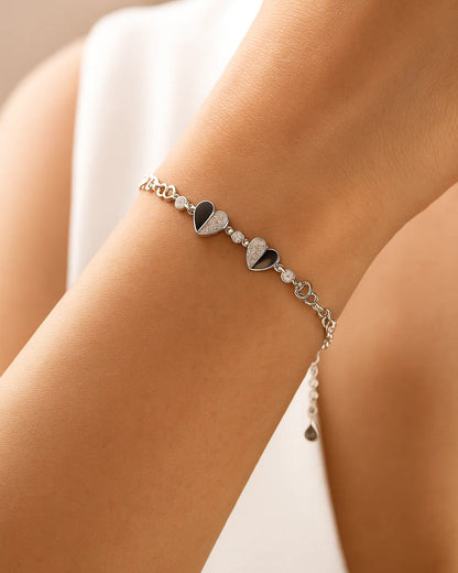 Silver bracelet with heart charms on a wrist against a neutral background