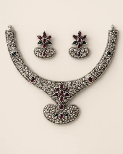 Ornate necklace and earrings set on a beige background