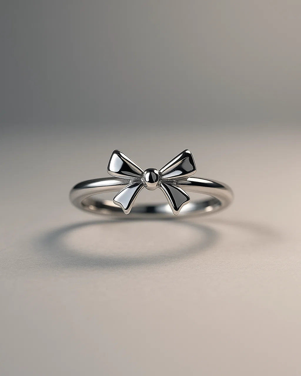 Silver bow-shaped ring on a gray background