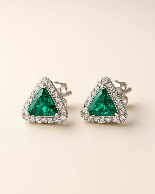 Pair of emerald green triangle earrings with diamond accents on a beige background