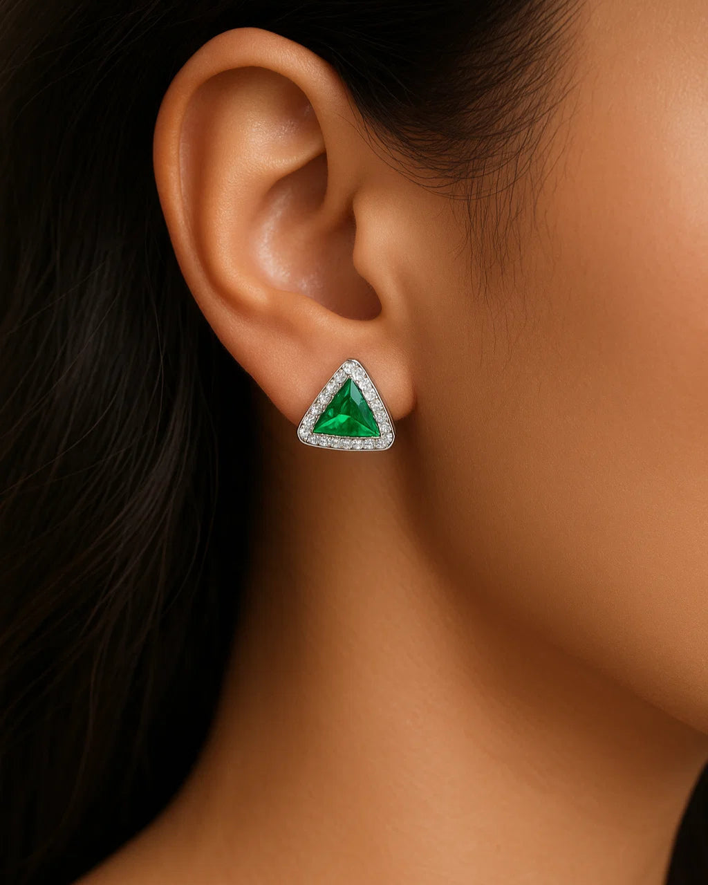 Close-up of an ear wearing a green gemstone earring with a blurred background