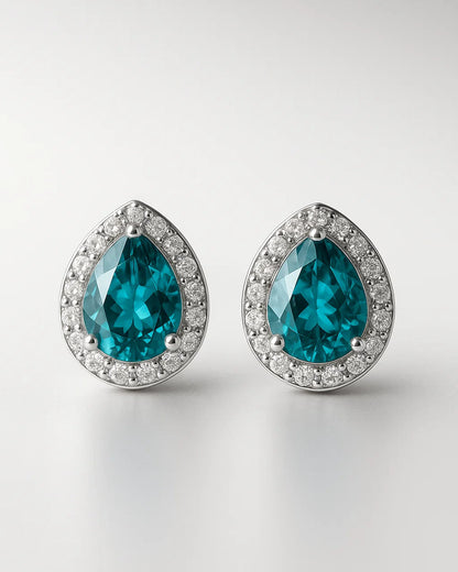 Pair of teal teardrop earrings with silver rims on a light gray background