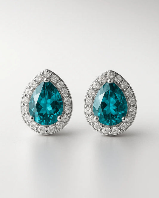 Pair of teal teardrop earrings with silver rims on a light gray background