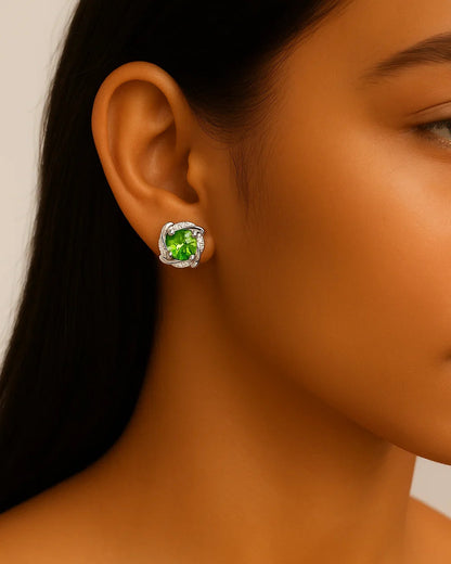 Close-up of a person wearing green gemstone earrings with a neutral background