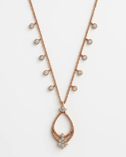 Rose gold necklace with teardrop pendant and small diamonds on a white background