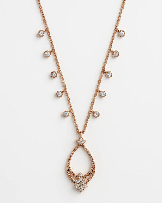 Rose gold necklace with teardrop pendant and small diamonds on a white background