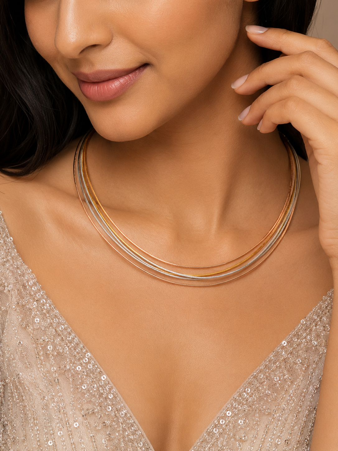 Close-up of a woman wearing a gold necklace with a neutral background