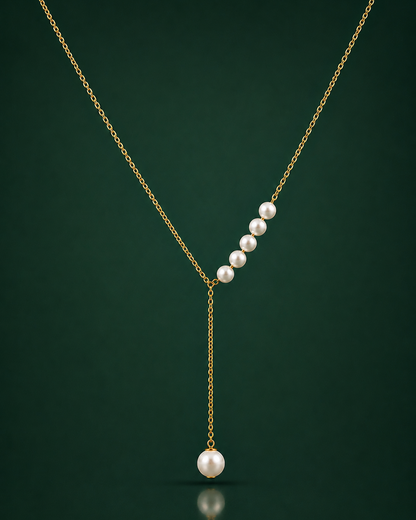 A golden Y-necklace featuring five white pearls aligned on one side and a single larger pearl hanging from the center, set against a dark green background.